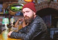 Man with beard spend leisure in dark bar. Brutal lonely hipster. Brutal hipster bearded man sit at bar counter. Friday