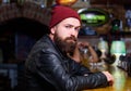 Man with beard spend leisure in dark bar. Brutal lonely hipster. Brutal hipster bearded man sit at bar counter. Friday