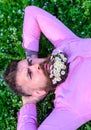 Man with beard on strict face enjoy nature. Bearded man with daisy flowers lay on grassplot, grass background Royalty Free Stock Photo