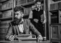 Man with beard and strict face work with typewriter