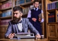 Man with beard and strict face work with typewriter