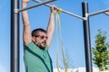 man with beard and sunglasses training his back by doing pull-ups on a bar in an outdoor gym Royalty Free Stock Photo