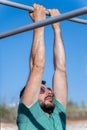 man with beard and sunglasses training his back by doing pull-ups on a bar in an outdoor gym Royalty Free Stock Photo