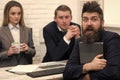 Man with beard on surprised face holds laptop, bosses, coworkers, colleagues on background. Man surprised, hired for Royalty Free Stock Photo