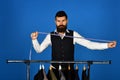 Man with beard takes measures by clothes rack with suits.