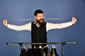 Man with beard takes measures by clothes rack with suits.