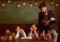 Man with beard teaches schoolgirls, reading book. Bored and tired children listening teacher. Teacher and girls pupils