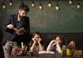 Man with beard teaches schoolgirls, reading book. Bored and tired children listening teacher. Teacher and girls pupils