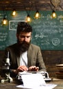 Man with beard typewrite research paper. Bearded man type on vintage typewriter. Businessman in suit work at desk