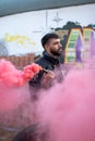 Man with beard and urban outfit holding a red smoke flare