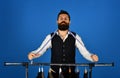 Man with beard in vest by clothes rack. Fashion choice