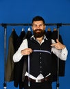 Man with beard by clothes rack. Shop assistant or seller