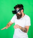 Man with beard in VR glasses, green background. Hipster on busy face use modern technologies for entertainment or