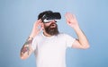 Man with beard in VR glasses, light blue background. VR gadget concept. Hipster on busy face exploring virtual reality