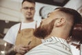 Man with beard waits for a shave with a razor in a barbershop