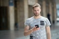 Man with beard walks with smartphone urban background. Guy use smartphone to send message or find location. Man use Royalty Free Stock Photo