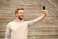 Man with beard walks with smartphone, urban background with stairs. Man blogger using video conferencing on smartphone