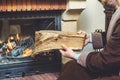 Man with beard wearing bathrobe puts log in burning fireplace Royalty Free Stock Photo