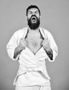 Man with beard in white kimono on red background. Japanese martial arts concept. Karate man with angry face