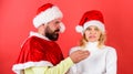 Man with beard and woman in santa hat on red background. Girl disgusted face celebrate christmas. Couple celebrate Royalty Free Stock Photo