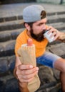 Man bearded bite tasty sausage and drink paper cup. Street food so good. Urban lifestyle nutrition. Carefree hipster eat