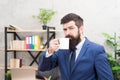 Man bearded businessman hold coffee cup stand office background. Start day with coffee. Successful people drink coffee Royalty Free Stock Photo