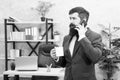 Man bearded businessman hold cup and smartphone. Coffee is pledge of successful negotiations. Caffeine addicted. Mobile