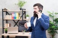 Man bearded businessman hold cup and smartphone. Coffee is pledge of successful negotiations. Caffeine addicted. Mobile