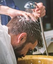 Man bearded client of hipster barbershop. Barbers hands washing hair of bearded hipster. Barbershop concept. Man with Royalty Free Stock Photo