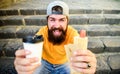 Man bearded enjoy quick lunch stairs background. Hipster eat hot dog drink coffee. Hipster enjoy hot dog drink paper cup