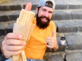 Man bearded enjoy street food stairs background. Hipster eat hot dog and drink coffee. Lunch time concept. Hipster enjoy Royalty Free Stock Photo