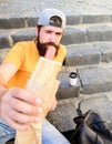 Man bearded enjoy street food urban background. Hipster eat hot dog while sit on stairs outdoors. Hipster enjoy hot dog Royalty Free Stock Photo