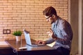 A man bearded freelancer with a laptop works in the evening.