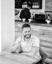 Man bearded guy drinks cappuccino wooden table cafe. Cafe visitor happy smiling face enjoy coffee drink. Improve overall