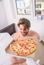 Man bearded handsome bachelor eating cheesy food for breakfast in bed. Man likes pizza for breakfast. Break diet concept