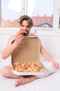 Man bearded handsome eat pizza. Man eat pizza breakfast. Guy naked covered pizza box sit bed bedroom offer you join him Royalty Free Stock Photo