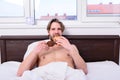 Man bearded handsome guy eating breakfast in bed. French breakfast stereotype. Man eats croissant and drinking coffee
