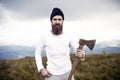 Man bearded hipster with axe stand on mountain landscape Royalty Free Stock Photo
