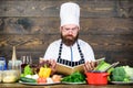 Man bearded hipster read book recipe near table fresh vegetables. Culinary arts. Recipe to cook healthy food. Vegetarian Royalty Free Stock Photo