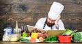 Man bearded hipster read book recipe near table fresh vegetables. Culinary arts. Recipe to cook healthy food Royalty Free Stock Photo