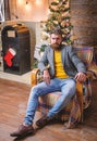 Man bearded hipster relax sit armchair near christmas tree. Feel like home. Man mature confident guy with beard relax at Royalty Free Stock Photo