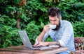 Man bearded hipster sit outdoors with laptop surfing internet and drinking coffee. Book apartment online. Guy looking Royalty Free Stock Photo