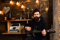 Man bearded musician enjoy evening with bass guitar, wooden background. Soul music. Man with beard holds black electric