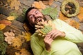 Man bearded smiling face lay on wooden background with orange leaves top view. Hipster with beard enjoy season hold
