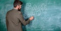 Man bearded teacher missed his work during vacation. Teacher near chalkboard holds chalk write inscription back to Royalty Free Stock Photo