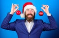 Man bearded wear formal suit and santa hat. Businessman join christmas celebration. Santa hold christmas ball decoration