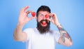 Man bearded winking with red berry, defocused. Look at my berry. Hipster happy enjoy juicy strawberry blue background