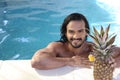 Man with beautiful olive skin using sun tan lotion in swimming pool Royalty Free Stock Photo