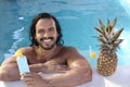 Man with beautiful olive skin using sun tan lotion in swimming pool Royalty Free Stock Photo