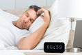 Man on bed with clock on nightstand